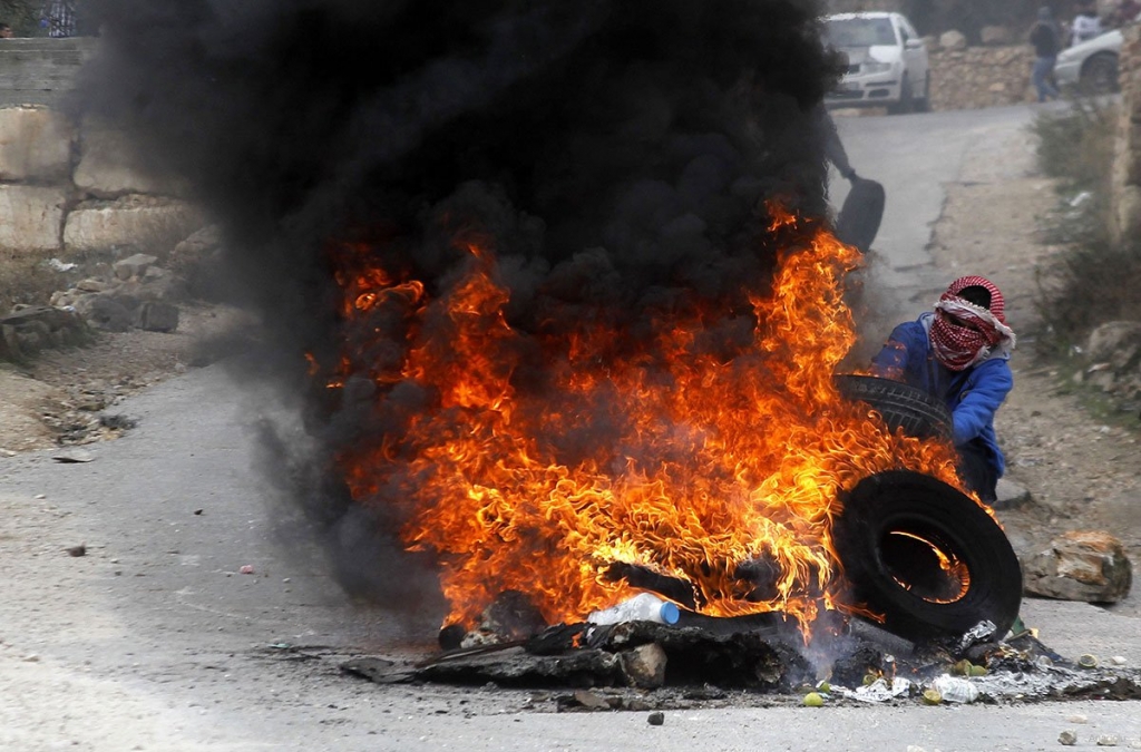 Palestinian protesters set tyres on fire during the clashes with Israeli forces following a demonstration against Israeli Government's violations over Palestinians in Hebron West Bank