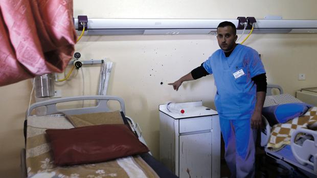 A medic shows a bullethole surrounded by bloodstains from a Palestinian man who was killed by Israeli undercover forces during a raid at Al Ahly hospital in Hebron yesterday