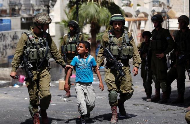 Israeli soldiers arrest a young Palestinian boy following clashes in the West Bank town of Hebron