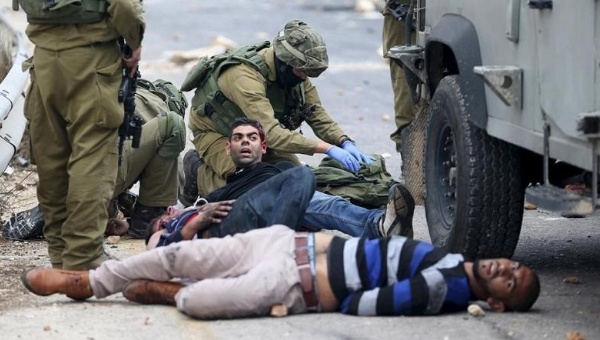 Israeli soldiers detain wounded Palestinian protesters during clashes near the Jewish settlement of Beit El