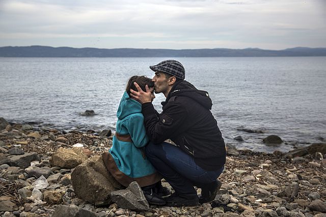 A Syrian man kisses his daughter shortly after disembarking from a dinghy at a beach on the Greek island of Lesbos after crossing the Aegean sea from the Turkish coast on Monday