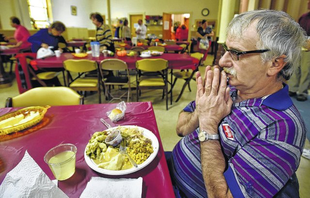 John Vecerkauskas prays before eating his meal at the First Baptist Church of Pittston during the church’s annual Thanksgiving dinner