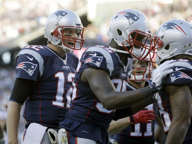 New England Patriots quarterback Tom Brady and defensive end Chandler Jones center congratulate running back Brandon Bolden right after his touchdown against the Washington Redskins during the second half of an NFL football game Sunday Nov. 8 2
