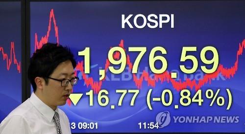 A currency trader walks past the screen showing the Korea Composite Stock Price Index at the foreign exchange dealing room in Seoul South Korea on Nov. 13 2015