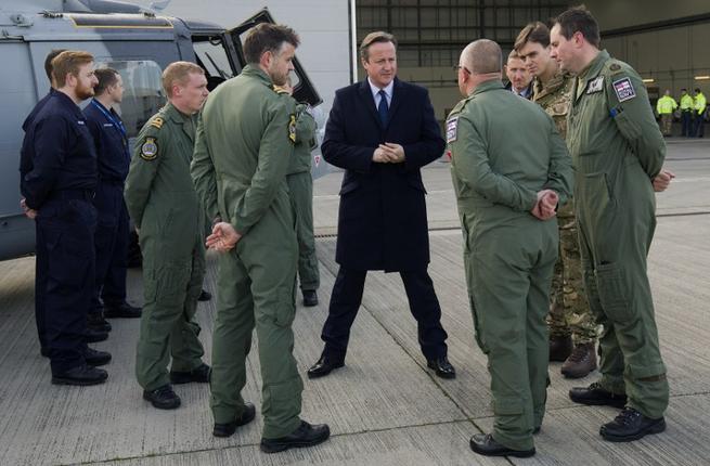 British Prime Minister David Cameron talks with Royal Navy personnel as they stand alongside a Royal Navy Wildcat multi-role helicopter in London