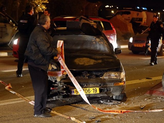 An Israeli forensic expert stands next to a car at the site of an attack that left one Israeli dead and eight wounded in the Jewish settlement bloc of Gush Etzion south of Jerusalem in the Israeli-occupied West Bank