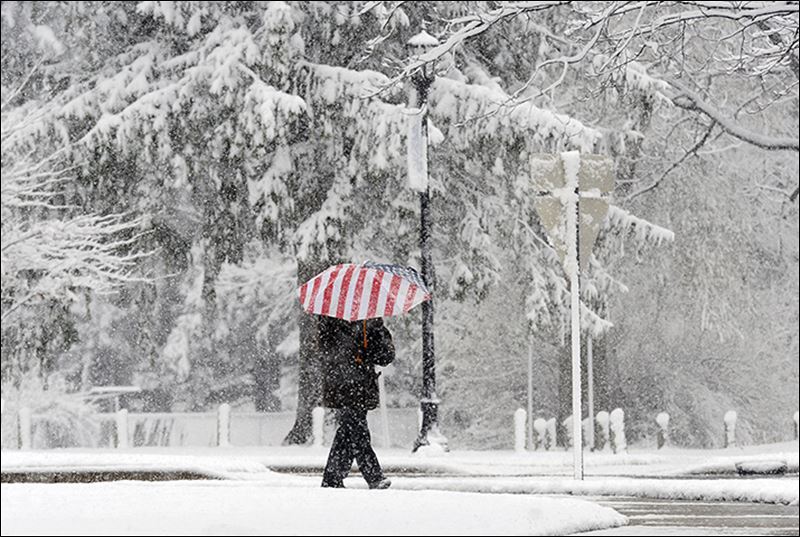 A pedestrian in Berrien Springs in western Michigan walks during the first significant snowfall of the season