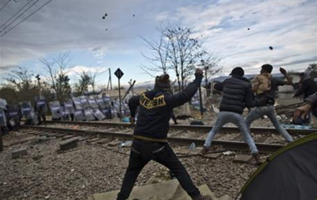 Migrants hurl stones at Macedonian policemen during clashes at the Greek Macedonian border near the northern Greek village of Idomeni on Saturday Nov. 28 2015. Tension has flared on the Greek side of the Greece Macedonia border when a migrant who was