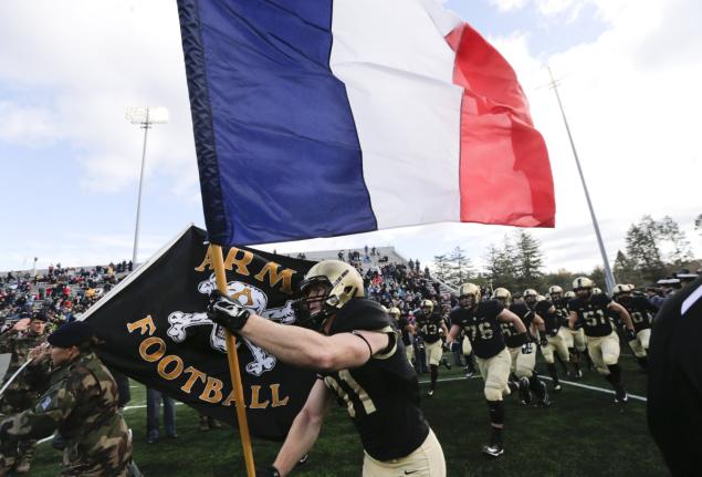 Army defensive back Caleb Mc Neill carries the flag of France onto the field at West Point Saturday