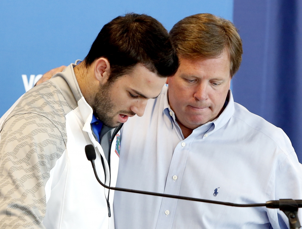 Florida Gators head coach Jim McElwain right puts his arm around quarterback Will Grier as Grier speaks to members of the media Monday Oct. 12 2015 in Gainesville Fla. Grier has been suspended indefinitely for violating the NCAA's policy on banned