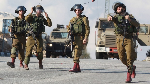 An Israeli soldier throws a sound grenade at Palestinian protesters during clashes in the West Bank city of Bethlehem