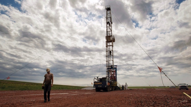 A worker walks by an oil derrick outside of Williston N.D. U.S. crude stockpiles are growing putting pressure on oil prices