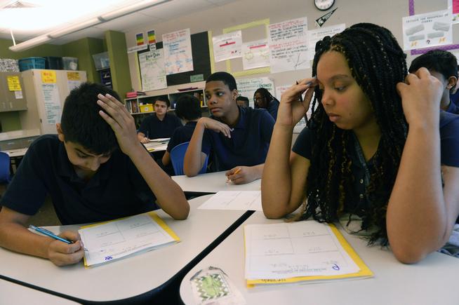 Eighth grader Neveah Hall 14 right and Eli Marin 13 right work on math problems during a math class at Boston K-8 school in Aurora