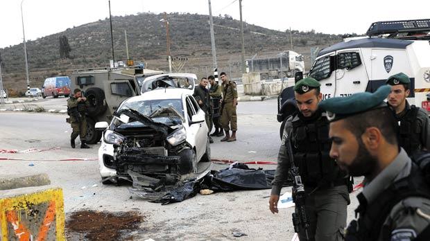 Israeli soldiers and paramilitary police stand at the scene of a car-ramming near the West Bank Jewish settlement of Tapuach south of Nablus yesterday