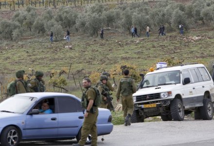 Israeli soldiers stand guard as Palestinians walk away from the scene of what the Israeli army said was a suspected Palestinian stabbing attack near the West Bank Al Fawwar refugee camp south of Hebr