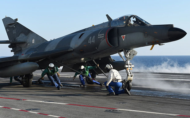 French navy soldiers prepare on the flight deck of the Charles de Gaulle aircraft carrier before a flight of a French Super Etendard jet fighter