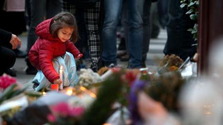 A young girl leaves a lit candle outside Le Carillon bar Paris one of the venues for the attacks