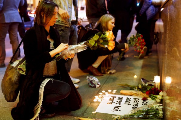 People place flowers at a makeshift memorial outside the Consulate General of France in San Francisco