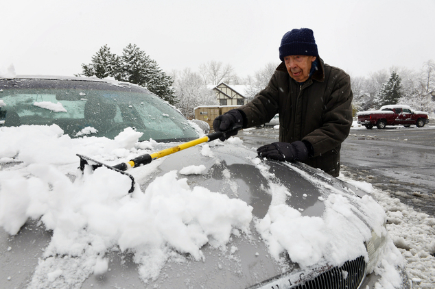 Ed Podrasky clears snow off his car as he gets ready to go to the store Saturday Nov. 21 2015 in Arlington Heights Ill. The first significant snowstorm