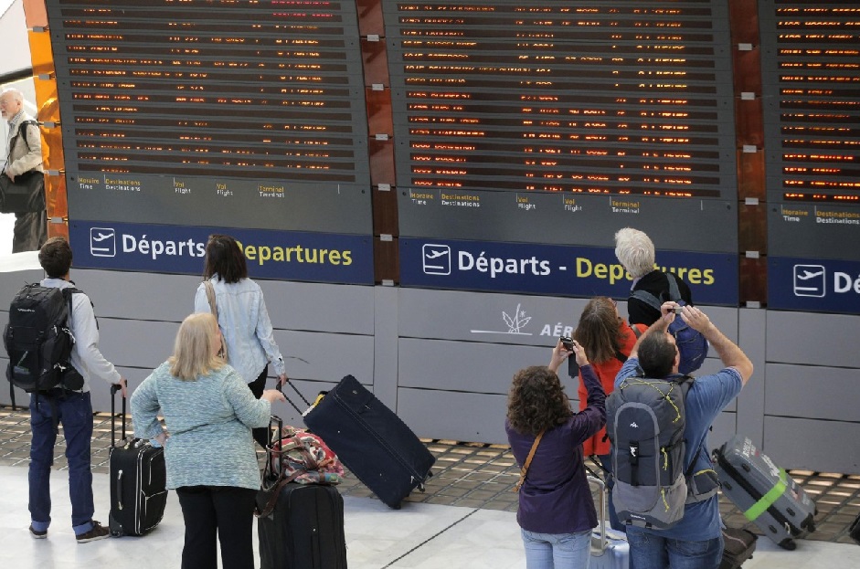 Passengers in front of the departures board at Charles de Gaulle Airport