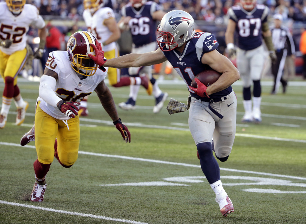 New England Patriots wide receiver Julian Edelman gives a stiff arm to Washington defensive back Jeron Johnson after catching a pass during the second half Sunday in Foxborough Mass