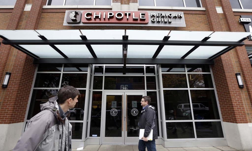 Pedestrians walk past a still-closed Chipotle restaurant Monday Nov. 9 2015 in Seattle