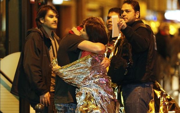 People hug each other before being evacuated by bus near the Bataclan concert hall in central Paris