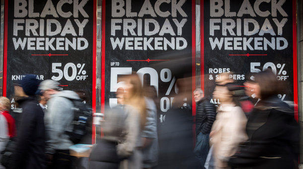 People walk past a shop advertising 'Black Friday&#039 discounts