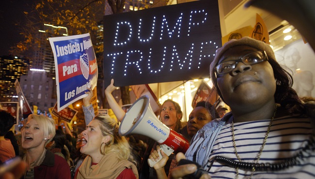 Sasha Murphy of the ANSWER Coalition leads demonstrators in a chant during a protest against Republican presidential candidate Donald Trump's hosting'Saturday Night Live in New York Saturday Nov. 7 2015. Despite a 40-year history of lampooning