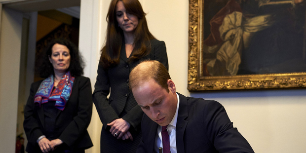 Princess Catherine watches as Prince William writes in a book of condolence at the French embassy in London