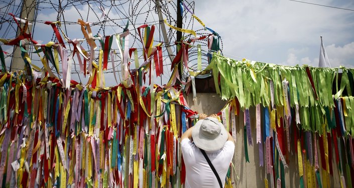 A tourist hangs a ribbon bearing messages wishing the unification of the two Koreas on a barbed-wire fence at the Imjingak pavilion near the demilitarized zone separating the two Koreas in Paju South Korea