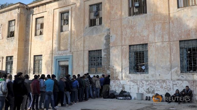 Refugees and migrants line-up during free food distribution at a temporary camp on the Greek island of Leros