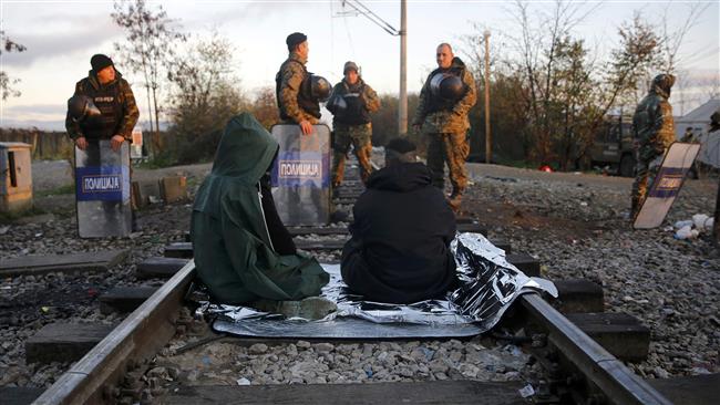 Stranded Iranian refugees sit on rail tracks in front of Macedonian police during a protest at the Greek Macedonian border near the Greek village of Idomeni