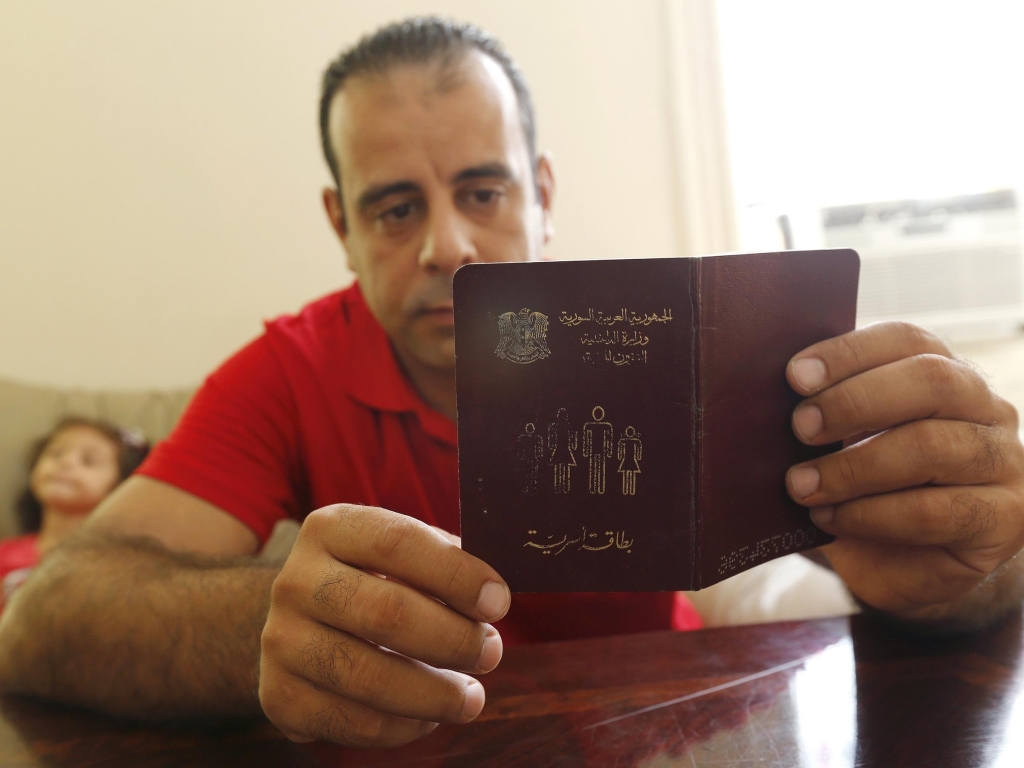 Syrian refugee Hussam Alroustom who fled with his wife and two young children looks over a booklet with identification information in his family's apartment in Jersey City N.J. in September. The U.S. has resettled around 1,800 refugees from Syria