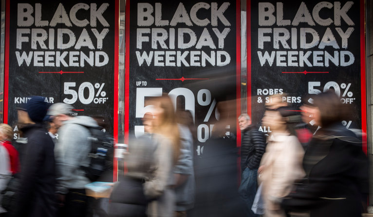 Rob Stothard  Getty Images People walk past a shop advertising'Black Friday discounts