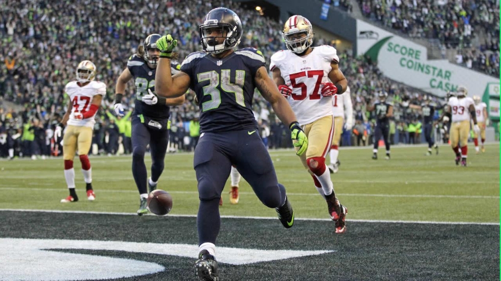 Thomas Rawls drops the ball after scoring a touchdown ahead of 49ers Michael Wilhoite during an NFL football game Sunday Nov. 22 2015 in Seattle