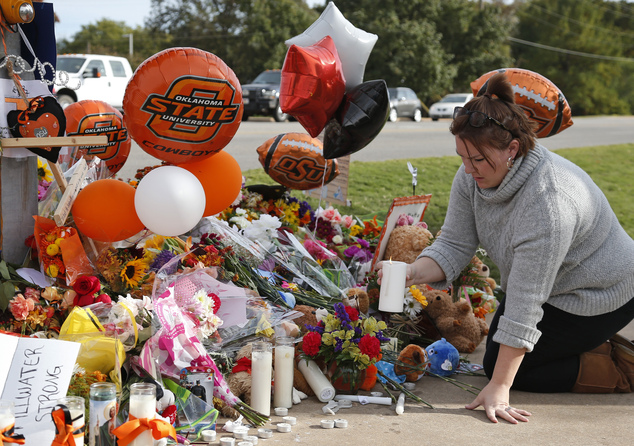 Stefanie Alexander who witnessed the Saturday homecoming parade crash places a candle at a makeshift memorial to the victims in Stillwater Okla. Monday