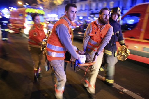 A woman is being evacuated from the Bataclan theater after a shooting in Paris Friday Nov. 13 2015. French President Francois Hollande declared a state of emergency and announced that he was closing the country's borders