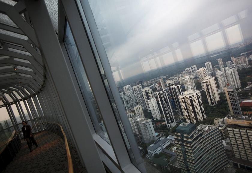 People walk on an observation deck overlooking high-rise residential condominium properties in the prime Orchard Road district in Singapore. Sales of private homes by developers in Singapore fell 30% in October from a year earlier. – Reuters pic Novemb