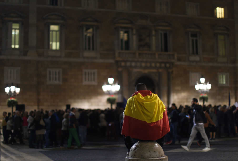 A man wraps with a Spanish flag during a demonstration calling for the “unity of Spain” in Barcelona Spain Thursday Nov. 5 2015. Three anti-independence parties filed complaints Wednesday before Spain’s Constitutional Court against moves by the