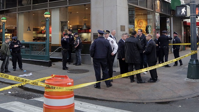 New York Police Department officers investigate a shooting near a subway station entrance at 35th Street and Eighth Avenue Monday Nov. 9 2015 in New York