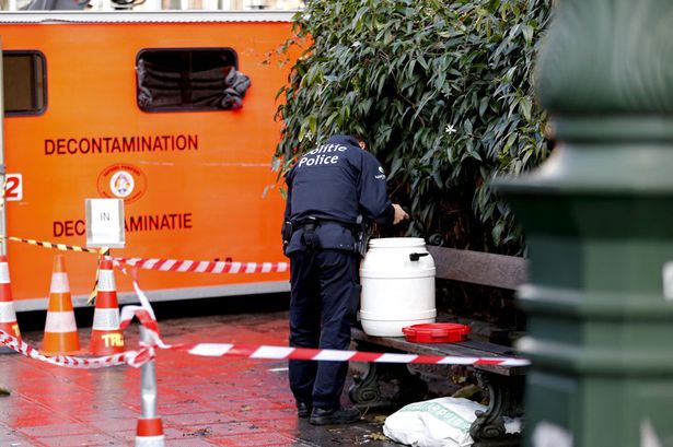 A Belgian police officer looks into a container outside the Grand Mosque