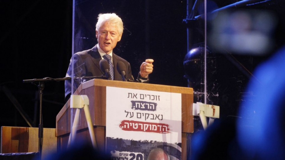 Former US president Bill Clinton delivers a speech behind a bulletproof glass during a rally marking 20 years since the assassination of the late Israeli prime minister Yitzhak Rabin at Tel Aviv's Rabin Square