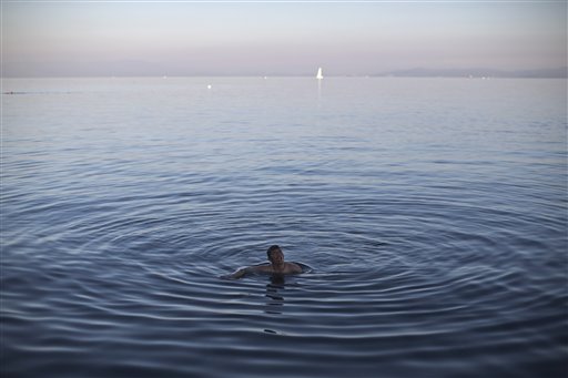 An Afghan man swims in the Aegean sea as he waits for a ferry to transport him to Athens in the port of Mytilene on the island of Lesbos Greece Wednesday Nov. 4 2015. Thousands of migrants and refugees are stranded on Lesbos due to a ferry strike tha