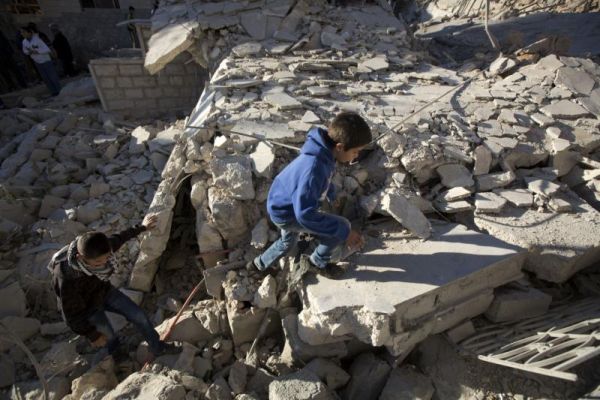 Palestinian youths walk on the rubble of