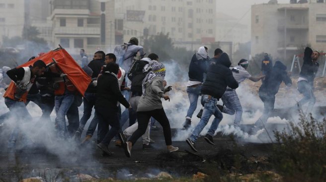 Palestinian protestors run during clashes with Israeli security forces in the Palestinian town of al Bireh on the outskirts of Ramallah in the Israeli-occupied West Bank