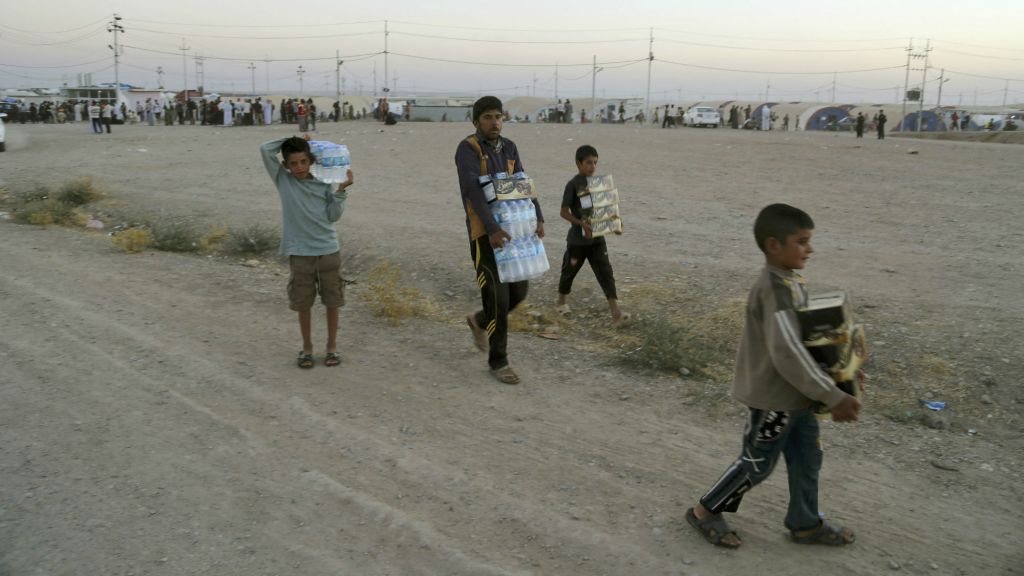 Displaced Iraqis from the Yazidi community carry humanitarian aid at the camp of Bajid Kandala at Feeshkhabour town near the Syria Iraq border in Iraq Saturday