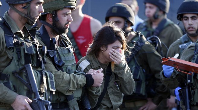 An Israeli female soldier reacts at the scene of a reported stabbing attack carried out by a Palestinian man against two Israeli soldiers killing one of them at a gas station on a main road. AFP