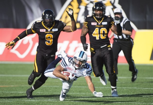 Toronto Argonauts wide receiver Diontae Spencer gets tripped up by Hamilton Tiger Cats defensive back Brandon Stewart and Hamilton Tiger-Cat