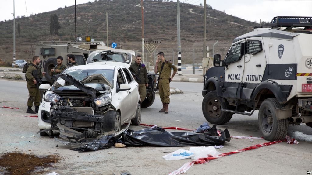 Israeli soldiers and border police officers stand near the body of a Palestinian center who rammed his vehicle into a group of Israelis standing at a hitchhiking station in the West Bank near the Palestinian town of Nablus Nov. 8 2015